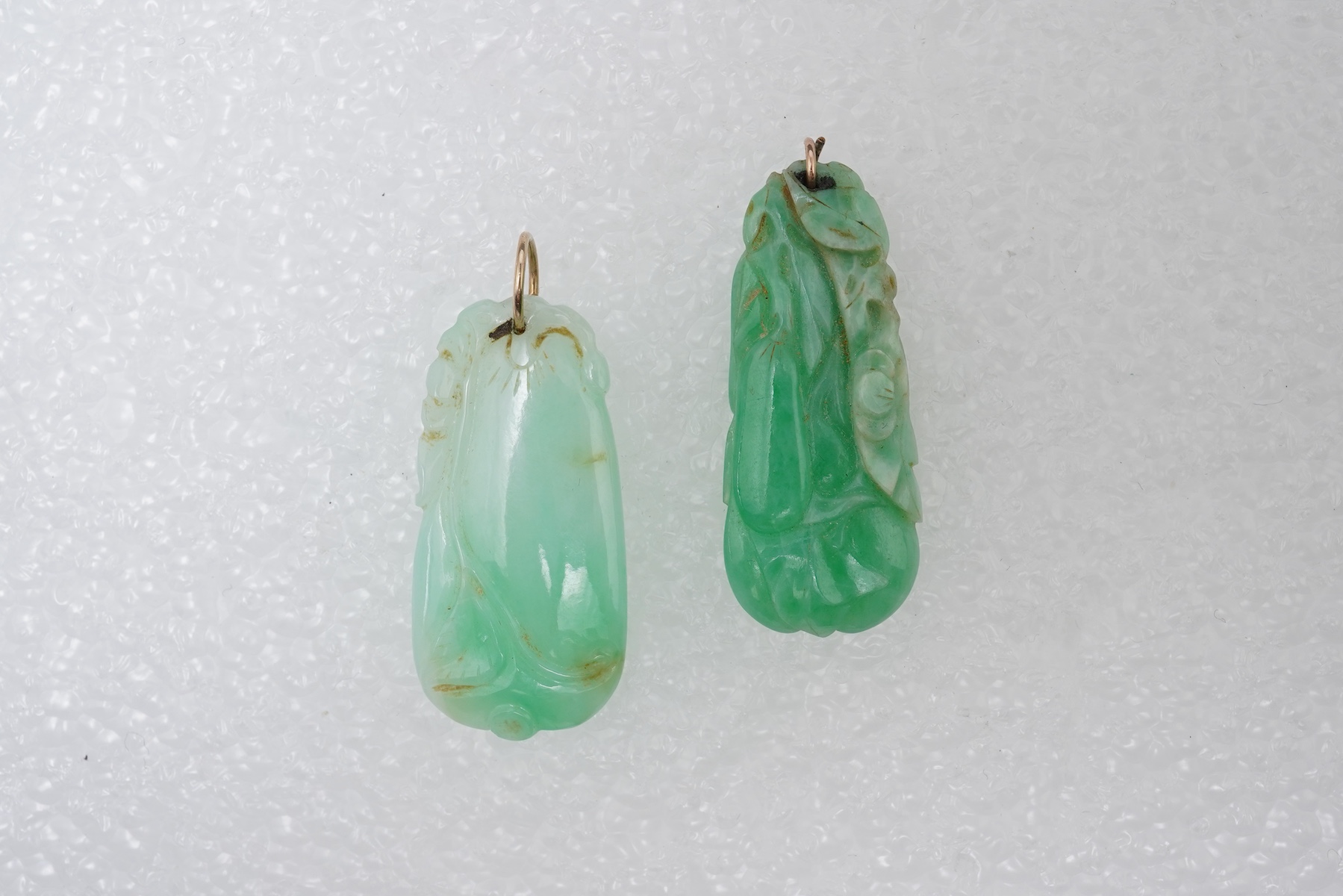 Two carved jadeite pendants, China, early 20th century, each carved to depict a fruiting vine of bitter gourd, longest 3.5cm excluding bail, combined gross weight approximately 10 grams